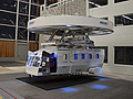 Hubschrauber-Simulator: eine realitätsnahe Hubschrauberkabine, die mittels Deckenkran gehoben und gesenkt in der Halle bewegt werden kann.