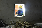 Ein Helfer sieht durch einen Mauerdurchbruch.